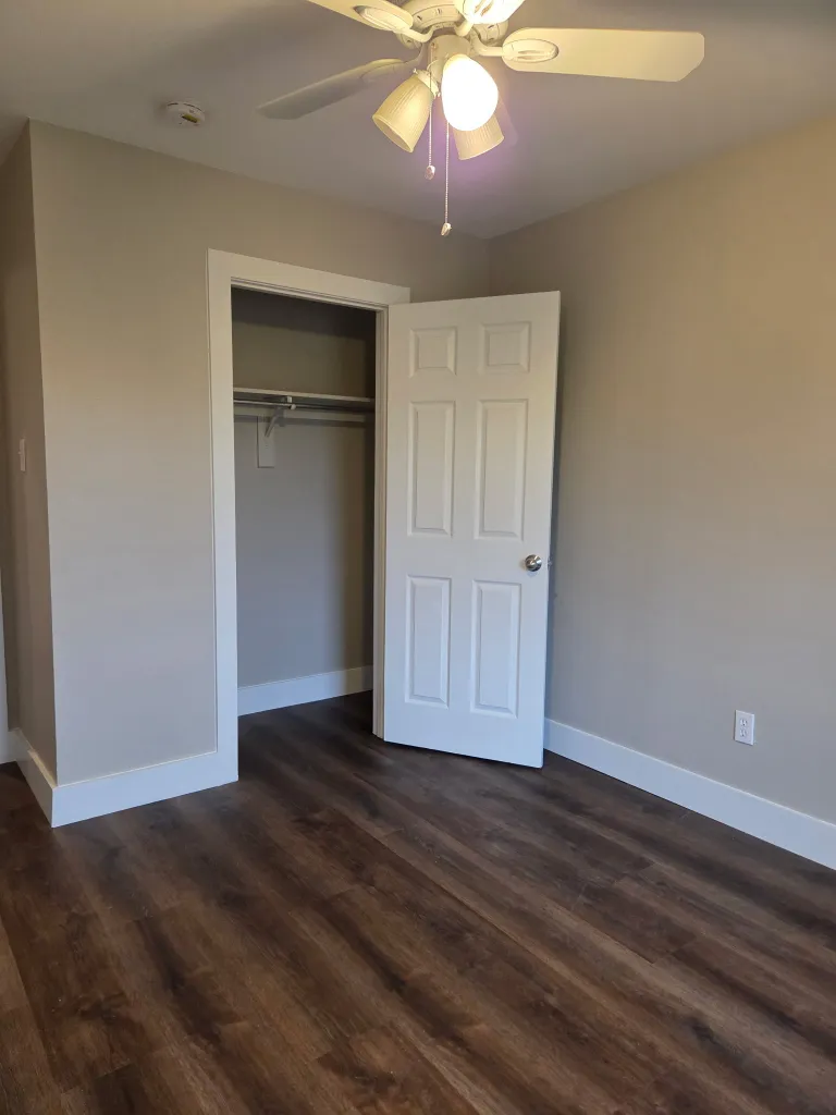 Completed residential restoration project showing restored bedroom with dark wood flooring and professional finish
