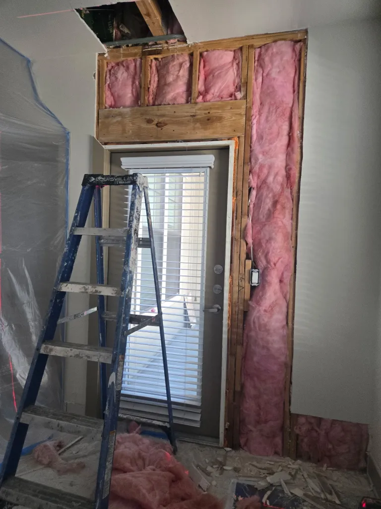 Extensive fire damage restoration showing structural repair with exposed framing and insulation replacement